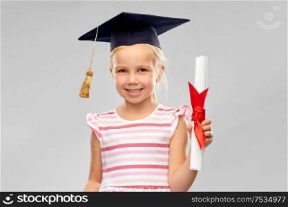 school, education and learning concept - happy little girl in bachelor hat or mortarboard with diploma over grey background. little girl in mortarboard with diploma