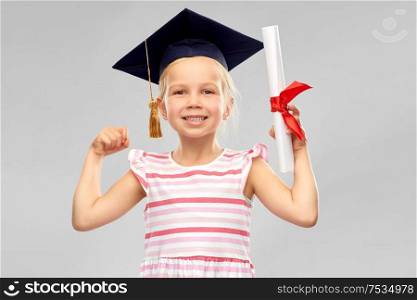 school, education and learning concept - happy little girl in bachelor hat or mortarboard with diploma over grey background. little girl in mortarboard with diploma
