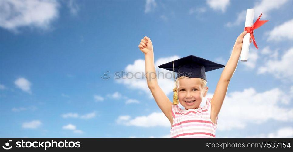 school, education and learning concept - happy little girl in bachelor hat or mortarboard with diploma celebrating success over blue sky and clouds background. happy little girl in mortarboard with diploma