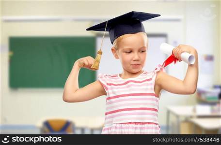 school, education and learning concept - happy little girl in bachelor hat or mortarboard with diploma over classroom background. little girl in mortarboard with diploma at school
