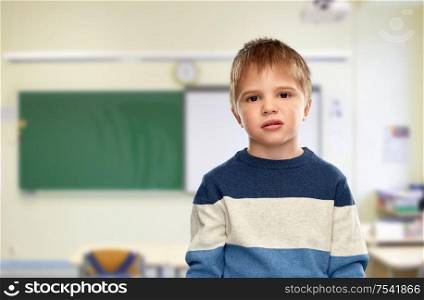 school, education and learning concept - portrait of little boy in striped pullover over classroom background. little boy in striped pullover at school