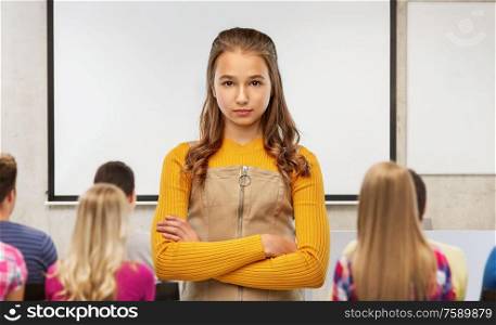 school, education and people concept - serious young teenage student girl with crossed arms over classroom background. serious student girl with crossed arms at school