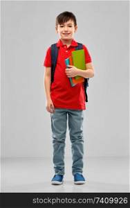 school, education and people concept - smiling little student boy in red polo t-shirt in glasses with books and bag over grey background. smiling student boy with books and school bag