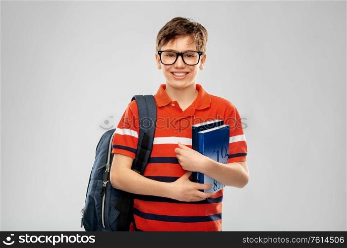 school, education and people concept - smiling student boy in glasses with backpack and books over grey background. smiling student boy with backpack and books
