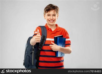 school, education and people concept - smiling student boy with backpack and books showing thumbs up over grey background. student boy with bag and books showing thumbs up