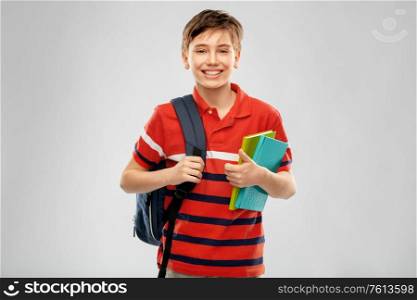 school, education and people concept - smiling student boy with backpack and books over grey background. smiling student boy with backpack and books