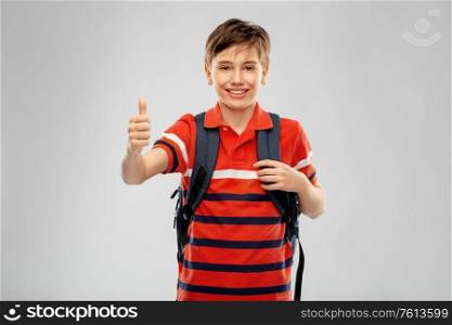 school, education and people concept - smiling student boy with backpack showing thumbs up over grey background. happy student boy with backpack showing thumbs up