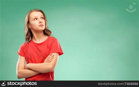 school, education and people concept - teenage girl in red t-shirt with crossed arms looking aside over green chalk board background. student girl with crossed arms over green