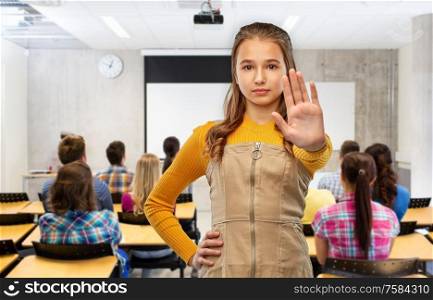 school, education and people concept - teenage student girl making stopping gesture over classroom background. student girl making stopping gesture at school