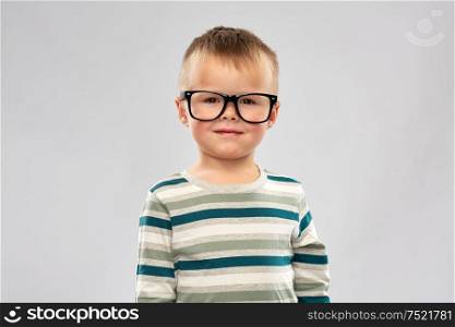 school, education and vision concept - portrait of smiling little boy in glasses over grey background. portrait of smiling little boy in glasses