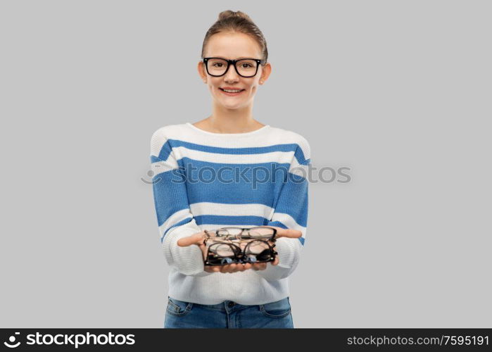 school, education and vision concept - smiling teenage student girl in glasses over grey background. smiling teenage student girl in glasses
