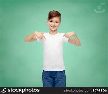 school, education, childhood, advertisement and people concept - happy boy in white t-shirt and jeans pointing finger to himself over green chalk board background