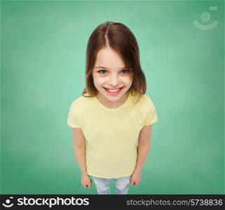 school, education, childhood and people concept - smiling little girl in blank t-shirt over green board background
