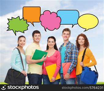 school, education, communication and people concept - group of smiling teenagers with folders and school bags over blue sky and grass background with doodles