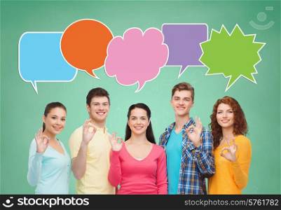 school, education, communication, gesture and people concept - group of smiling teenagers showing ok sign over green board background with text bubbles