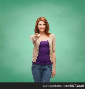 school, education, gesture and people concept - smiling teenage girl in casual clothes pointing finger on you over green board background