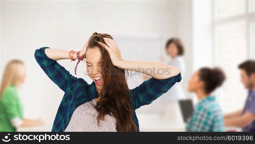 school, education, people and teens concept - happy pretty teenage student girl holding to head over classroom background with teacher and classmates