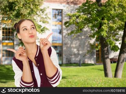 school, education, people and teens concept - happy pretty teenage student girl pointing finger over summer campus background