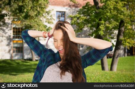 school, education, people and teens concept - happy pretty teenage student girl holding to head over summer campus background
