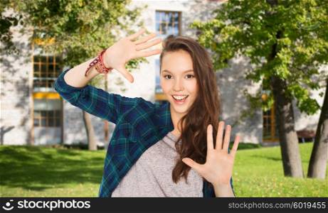 school, education, people and teens concept - happy smiling pretty teenage student girl showing hands over summer campus background