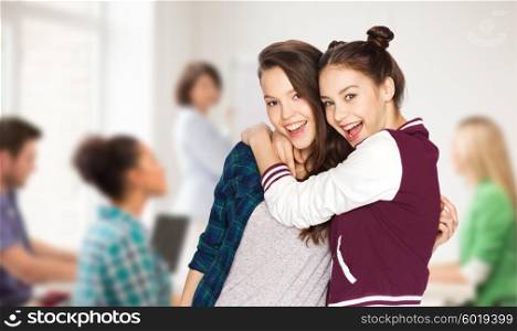 school, education, people, teens and friendship concept - happy smiling pretty teenage student girls hugging over classroom background with teacher and classmates