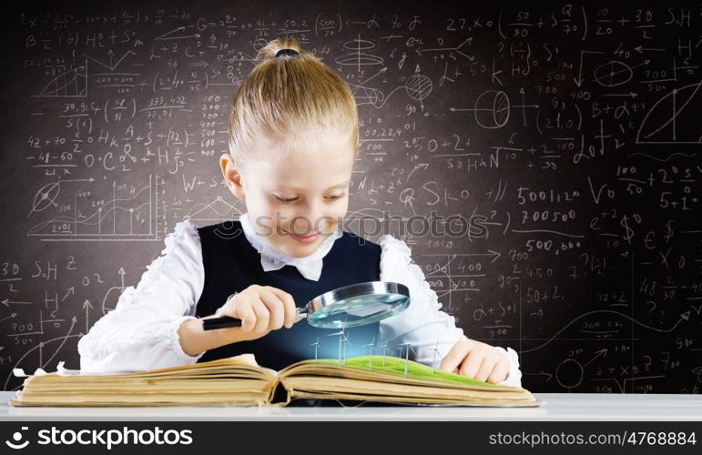 School education. Schoolgirl examining opened book with magnifying glass