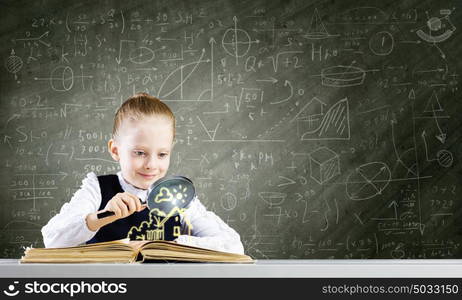 School education. Schoolgirl examining opened book with magnifying glass