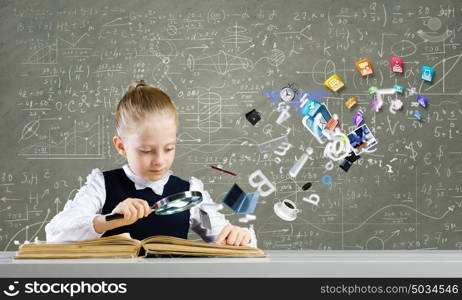 School education. Schoolgirl examining opened book with magnifying glass