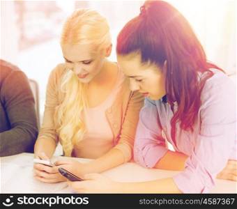 school, education, technology and internet concept - two teens with smartphones at school