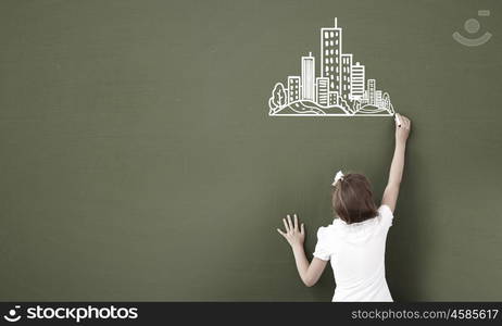 School girl at blackboard. Cute little girl standing with back and drawing on blackboard