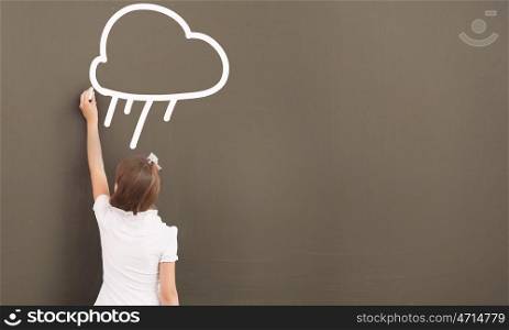 School girl at blackboard. Cute little girl standing with back and drawing on blackboard