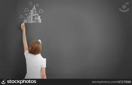School girl at blackboard. Cute little girl standing with back and drawing on blackboard