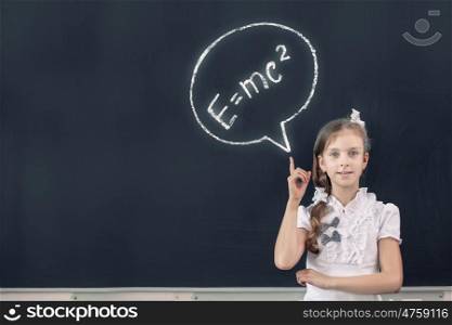 School girl at blackboard pointing at science formula with finger. Physics formula