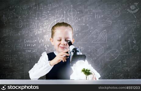 School girl at lesson. Cute girl with microscope against blackboard. Elements of this image are furnished by NASA