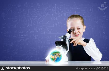 School girl at lesson. Cute girl with microscope against blackboard. Elements of this image are furnished by NASA