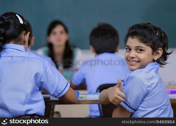 school girl smiling while teacher is sitting in class