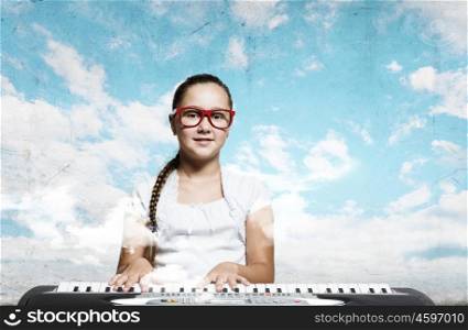 School girl with piano. Pretty school girl in funny glasses playing piano