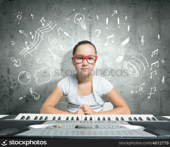 School girl with piano. Pretty school girl in funny glasses playing piano