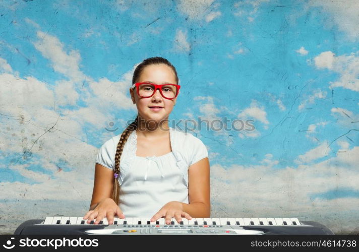 School girl with piano. Pretty school girl in funny glasses playing piano