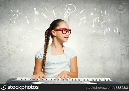 School girl with piano. Pretty school girl in funny glasses playing piano