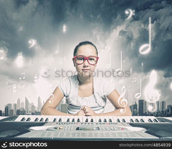 School girl with piano. Pretty school girl in funny glasses playing piano