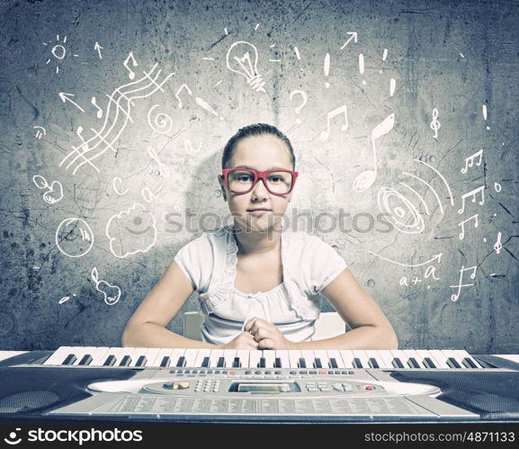 School girl with piano. Pretty school girl in funny glasses playing piano