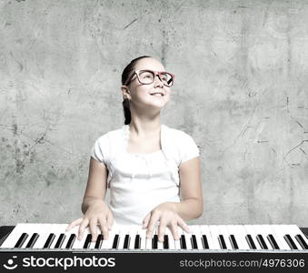 School girl with piano. Pretty school girl in funny glasses playing piano