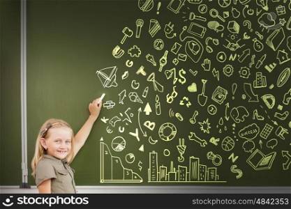 School girl writing chalk sketches on blackboard. That is my plan