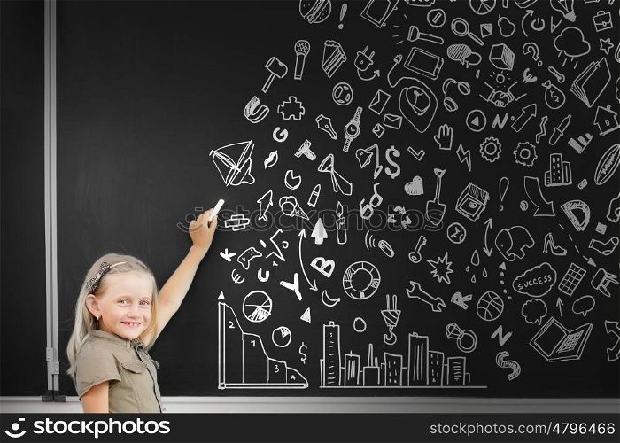 School girl writing graphs on blackboard with chalk. Back to school
