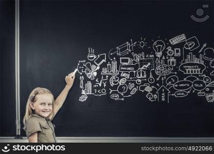 School girl writing graphs on blackboard with chalk. Back to school