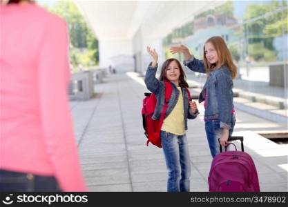 School girls waving goodbye at their mother