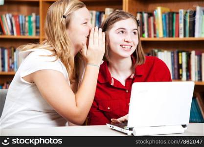 School girls whispering in the library.
