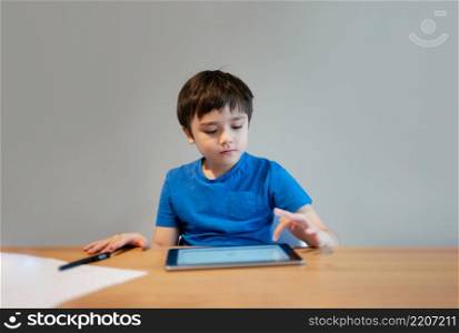School Kid learning online class room at home, Child using tablet for homework, Young boy studying online video call, E-learning or Homeschooling education concept