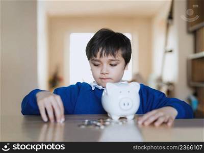 School kid putting coins into piggy bank, Child boy counting saving money, Young kid holding coin on his hands, Children learning financial responsibility and planning about saving money for future